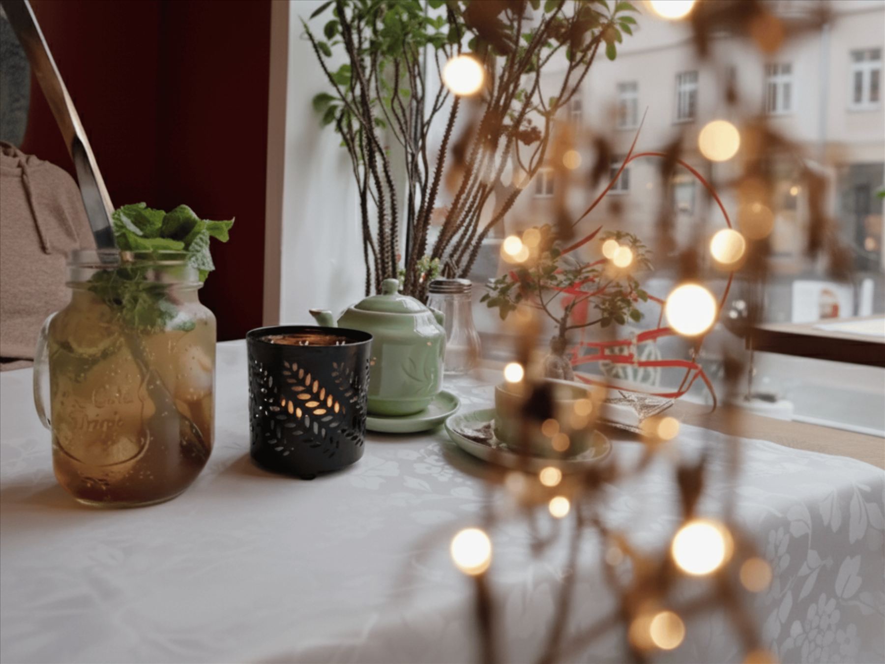 Tisch am Fenster mit Teekanne und Lichterkette